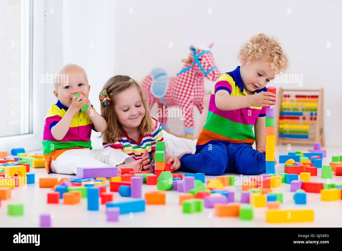 Happy preschool age children play with colorful plastic toy blocks. Creative kindergarten kids build a block tower. Stock Photo