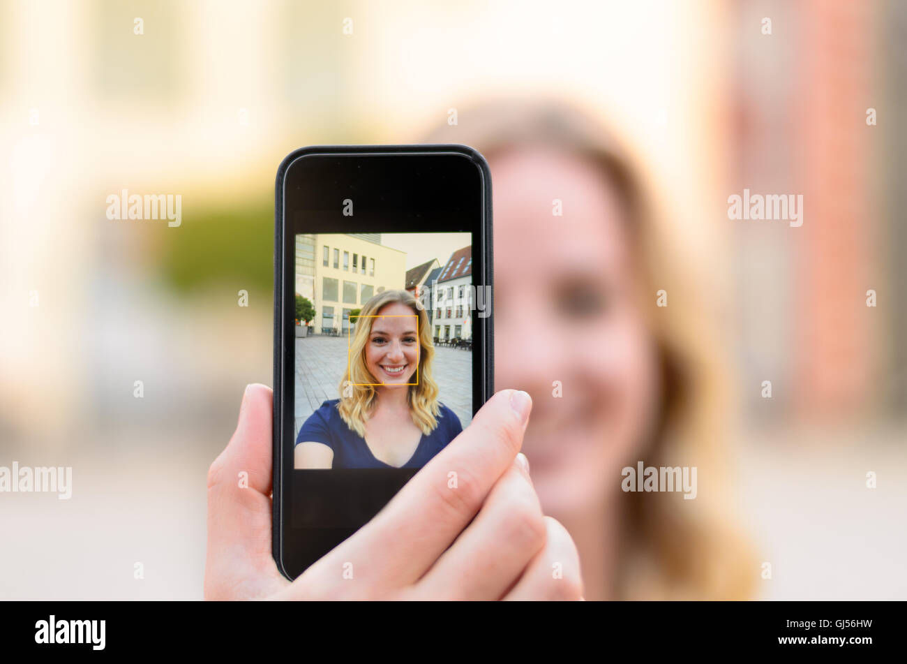 Happy attractive young blond woman taking a selfie outdoors in an urban ...