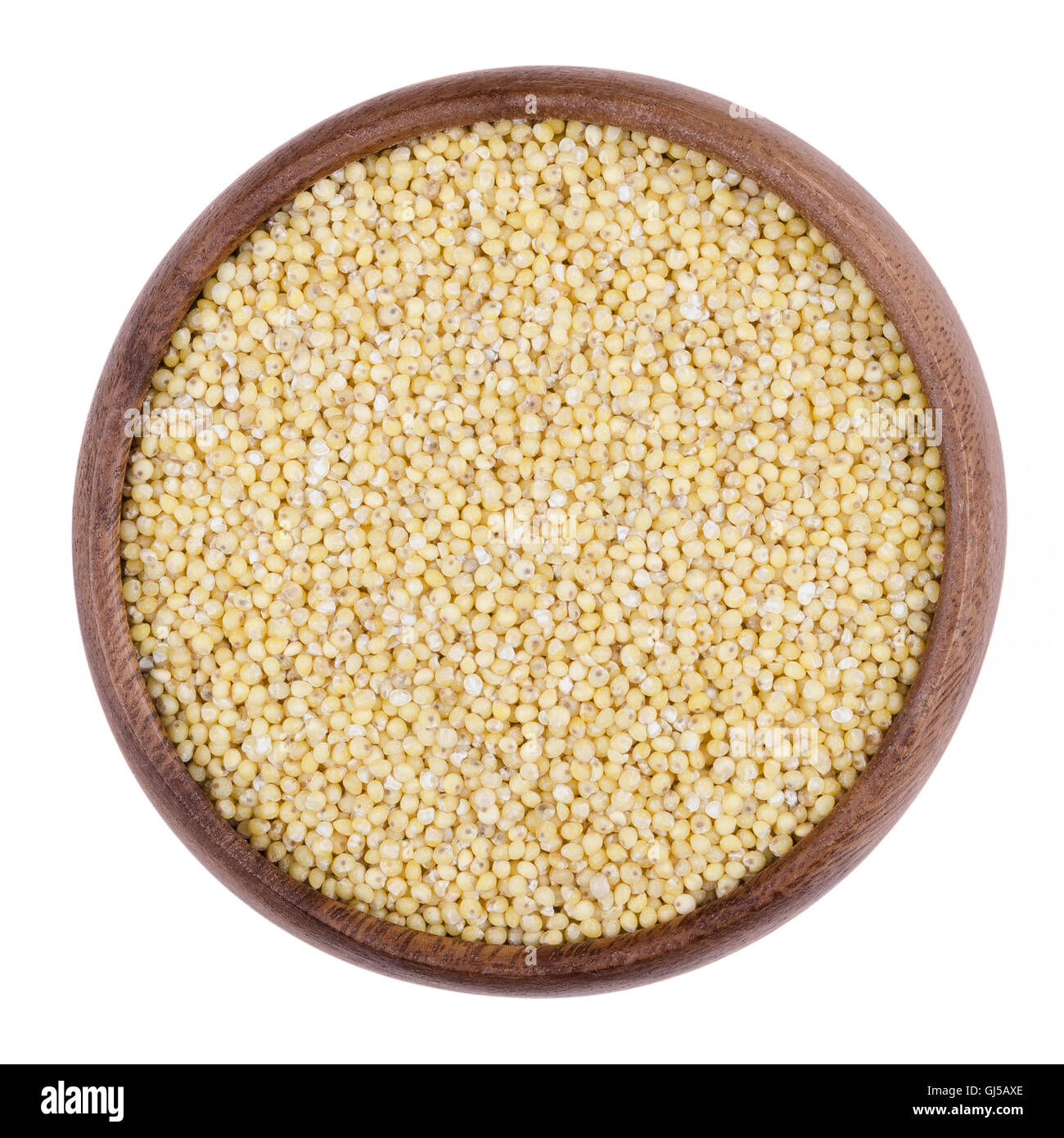 Yellow millet in a wooden bowl on white background. The small seeds are grown as cereal crops or grains. Stock Photo