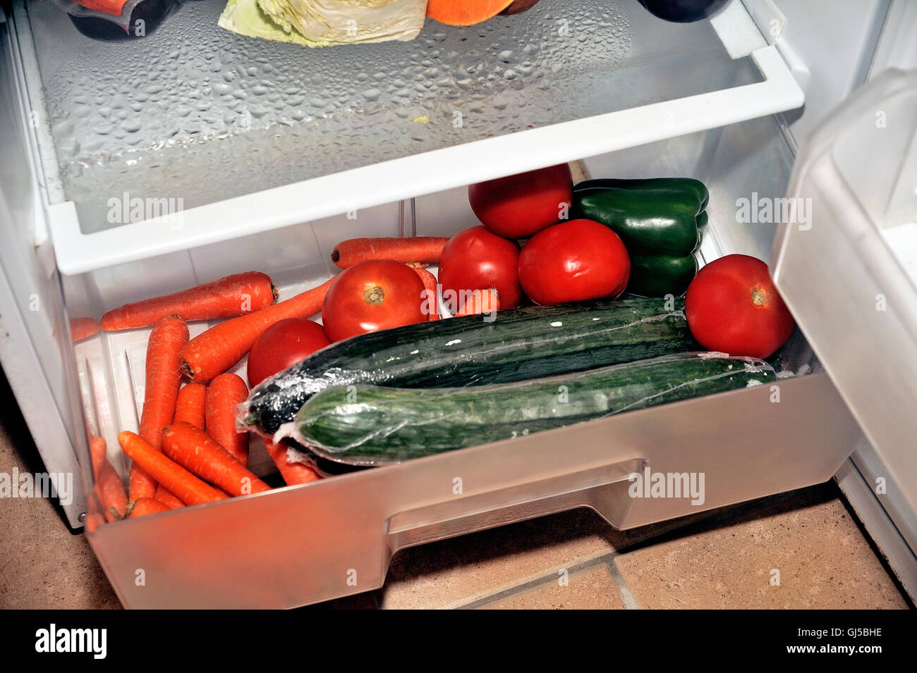 Open refrigerator containing food products each day as eggs, butter, cheese, sausage, meat and vegetables Stock Photo