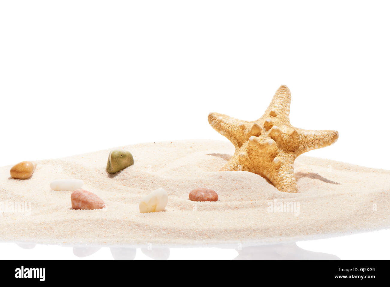 Starfish and sea stones on pile of beach sand isolated on white background Stock Photo
