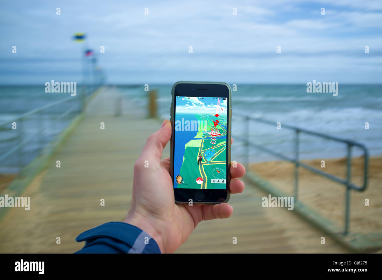 Melbourne, Australia - August 12, 2016: Male hand holding iPhone 6 with Pokemon Go game on a pier. Stock Photo