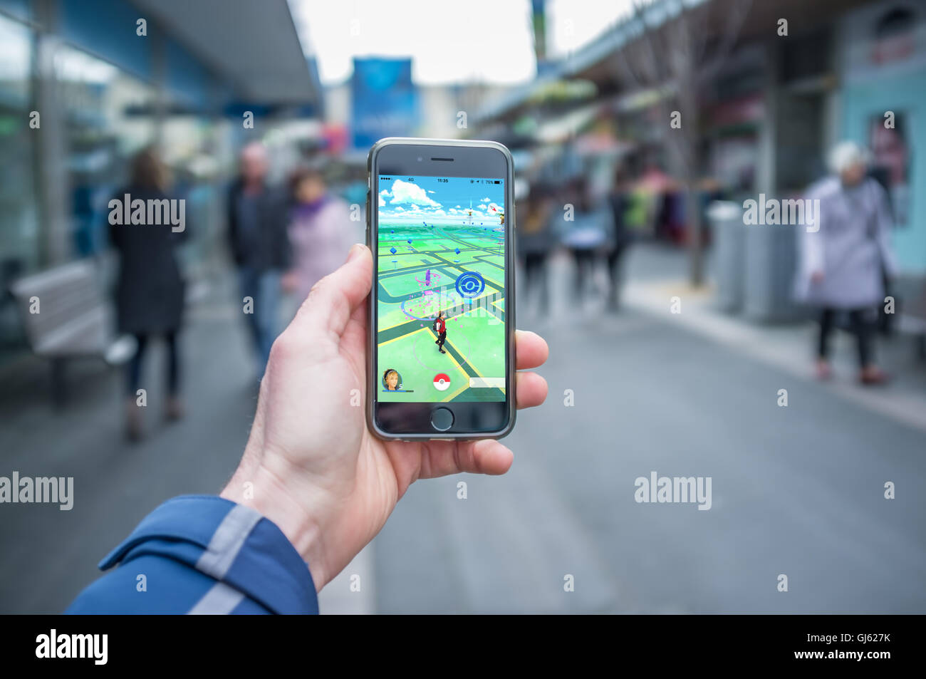 Melbourne, Australia - August 12, 2016: Male hand holding iPhone 6 with Pokemon Go game  on a busy street Stock Photo
