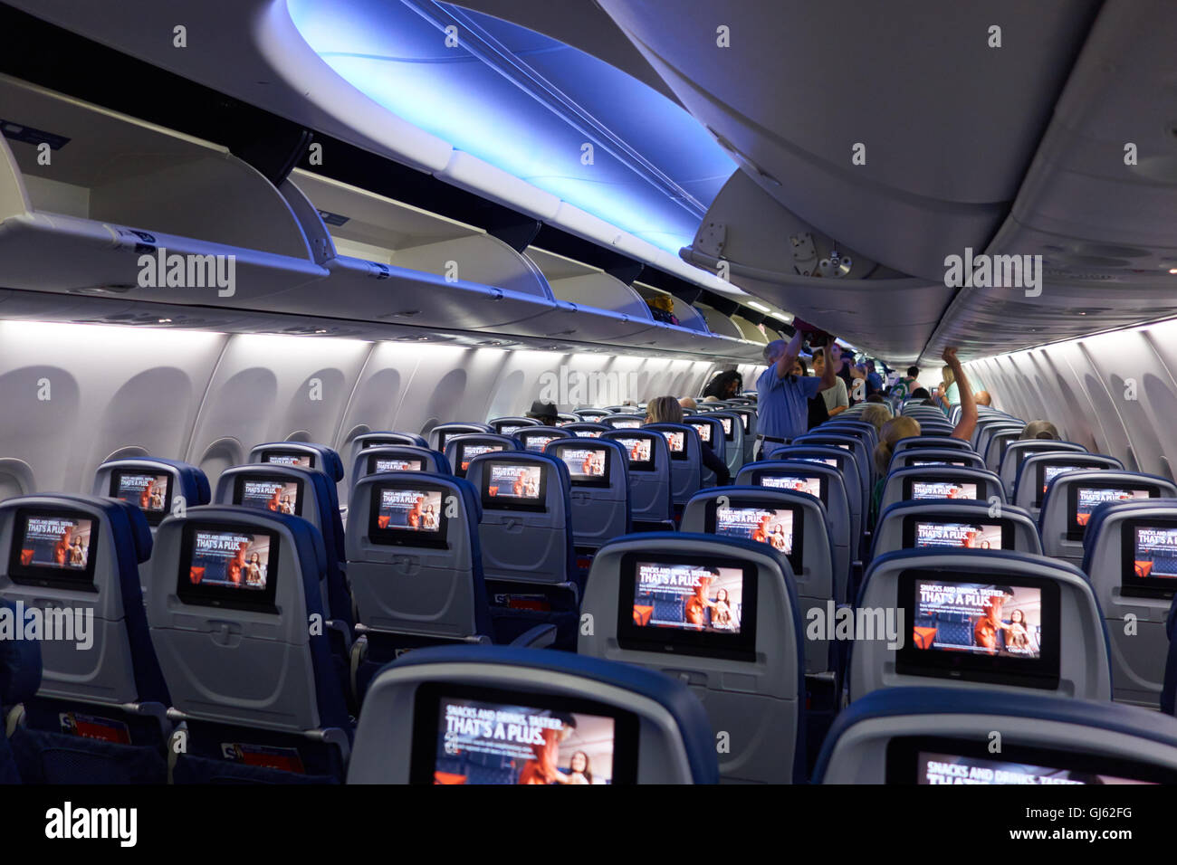 Inside  of jet airliner with passengers boarding and looking for seats. USA Stock Photo