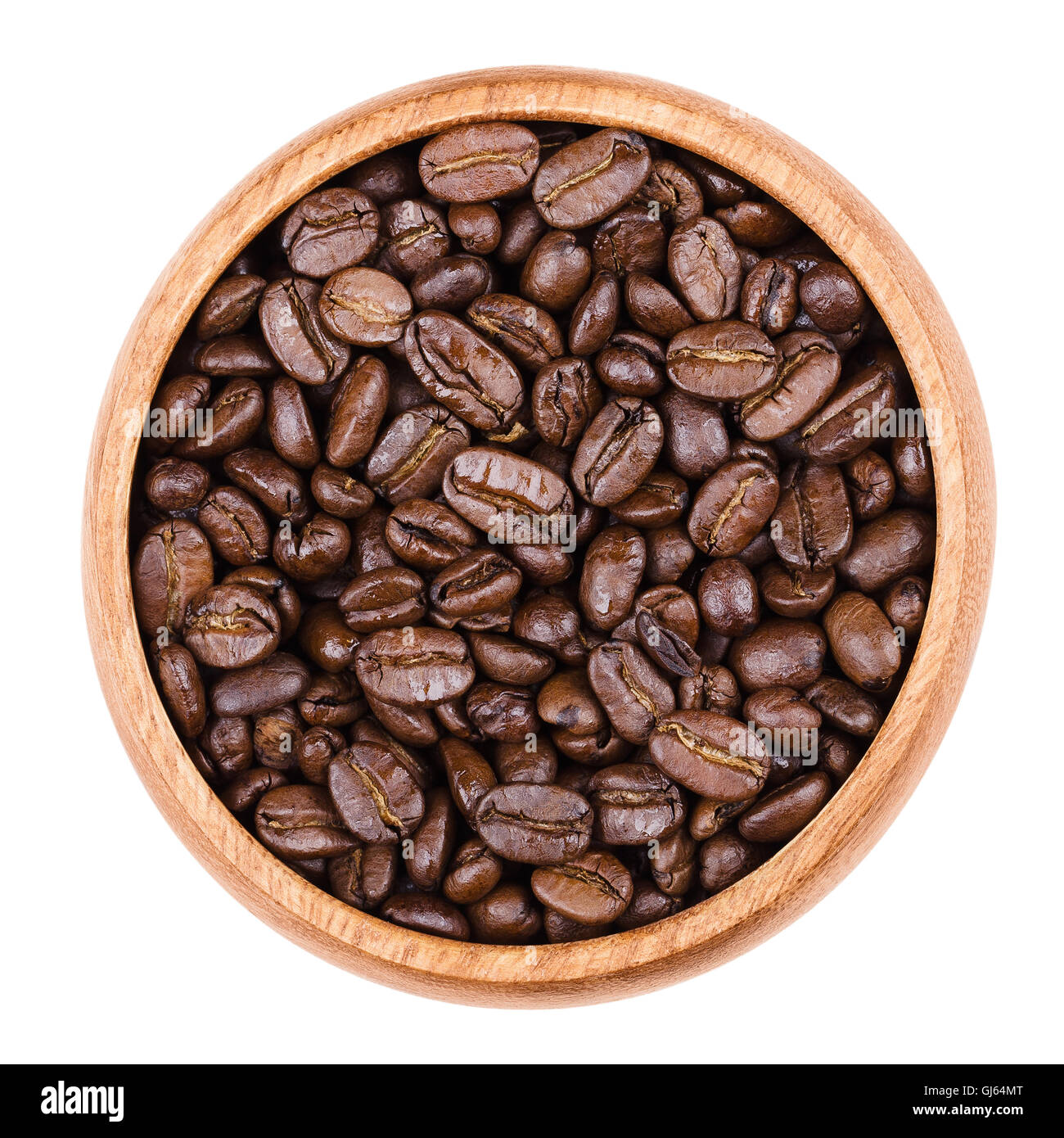 Arabica coffee beans in a wooden bowl on white background. Unpulverized roasted brown pits of the coffee cherries. Stock Photo