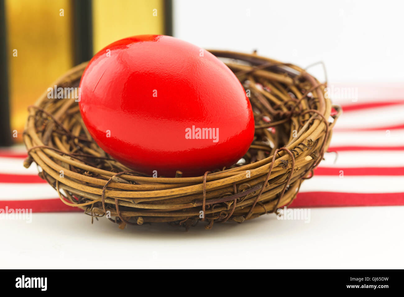 Red nest egg in front of books and red and white stripes of American flag. Stock Photo