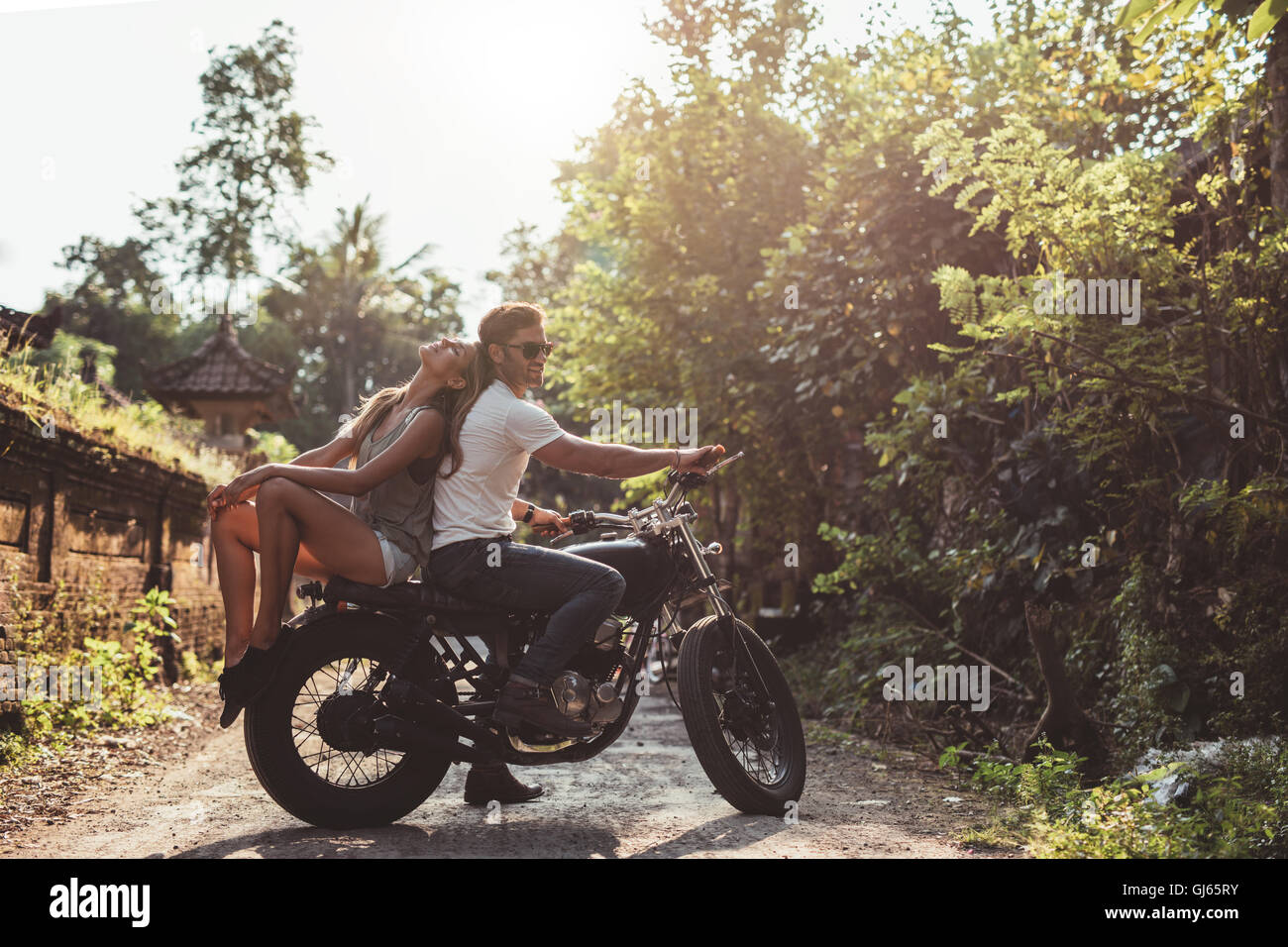 Young caucasian couple sitting out on a motorcycle. Young man and woman on motorbike on village road. Stock Photo