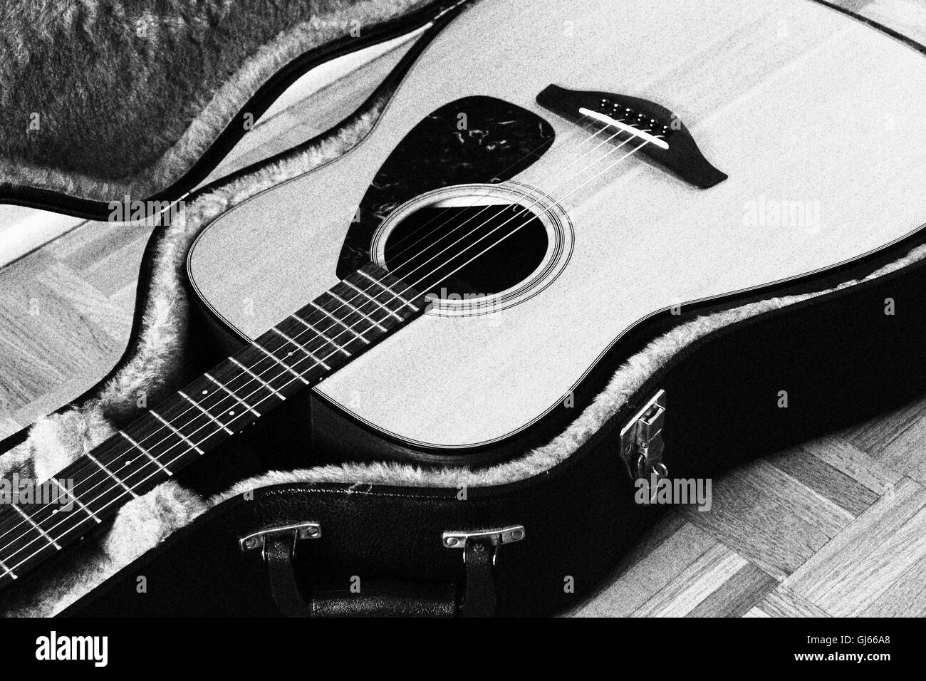 Old guitar resting in its soft sided hard case. ISO800. Picture filtered to Grainy black and white. Stock Photo