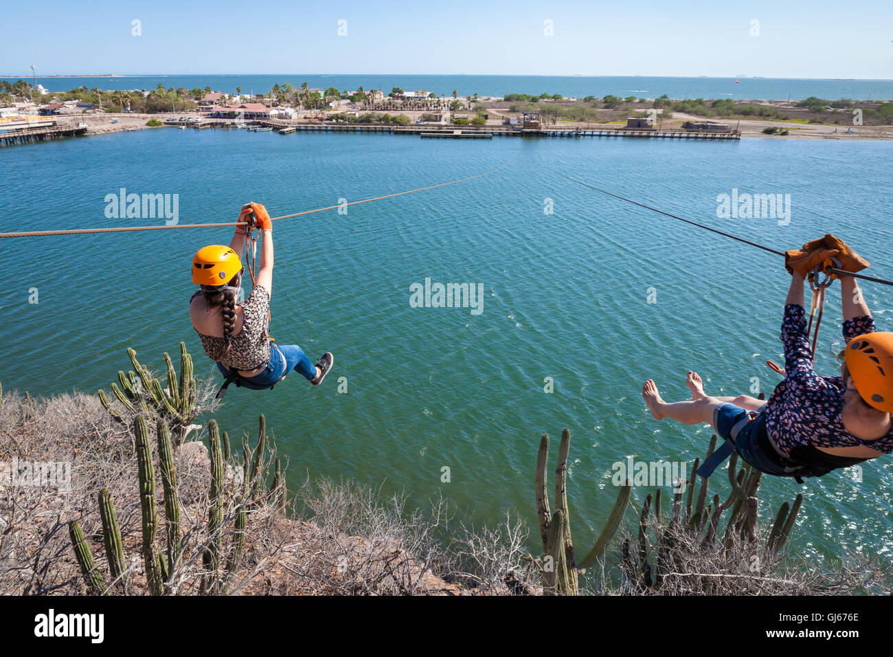 Mother and daughter set off across a small bay on the zipline at Maviri Beach near Topolobampo, Mexico. Stock Photo