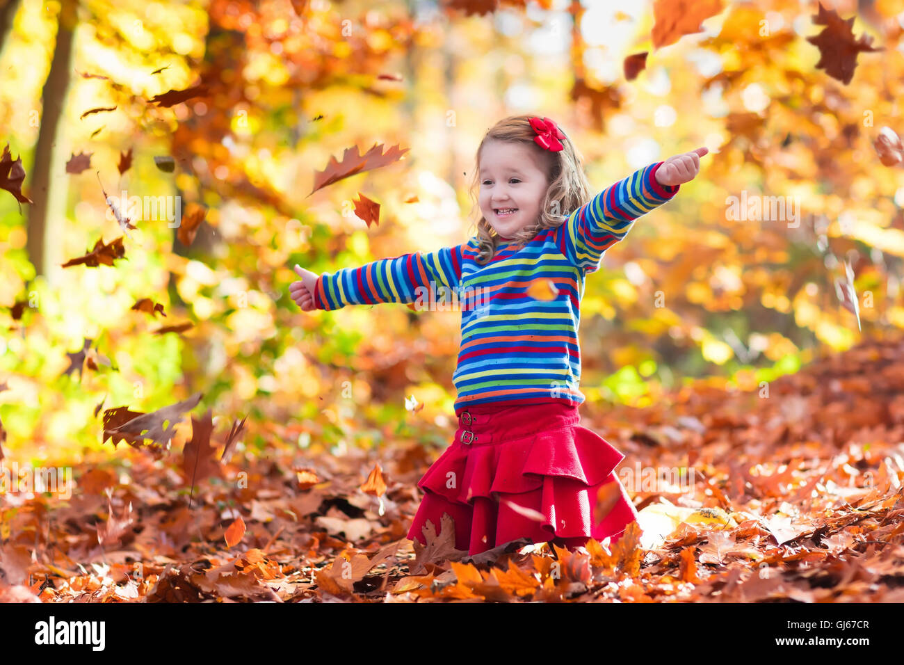 Happy little girl playing in beautiful autumn park on warm sunny fall ...