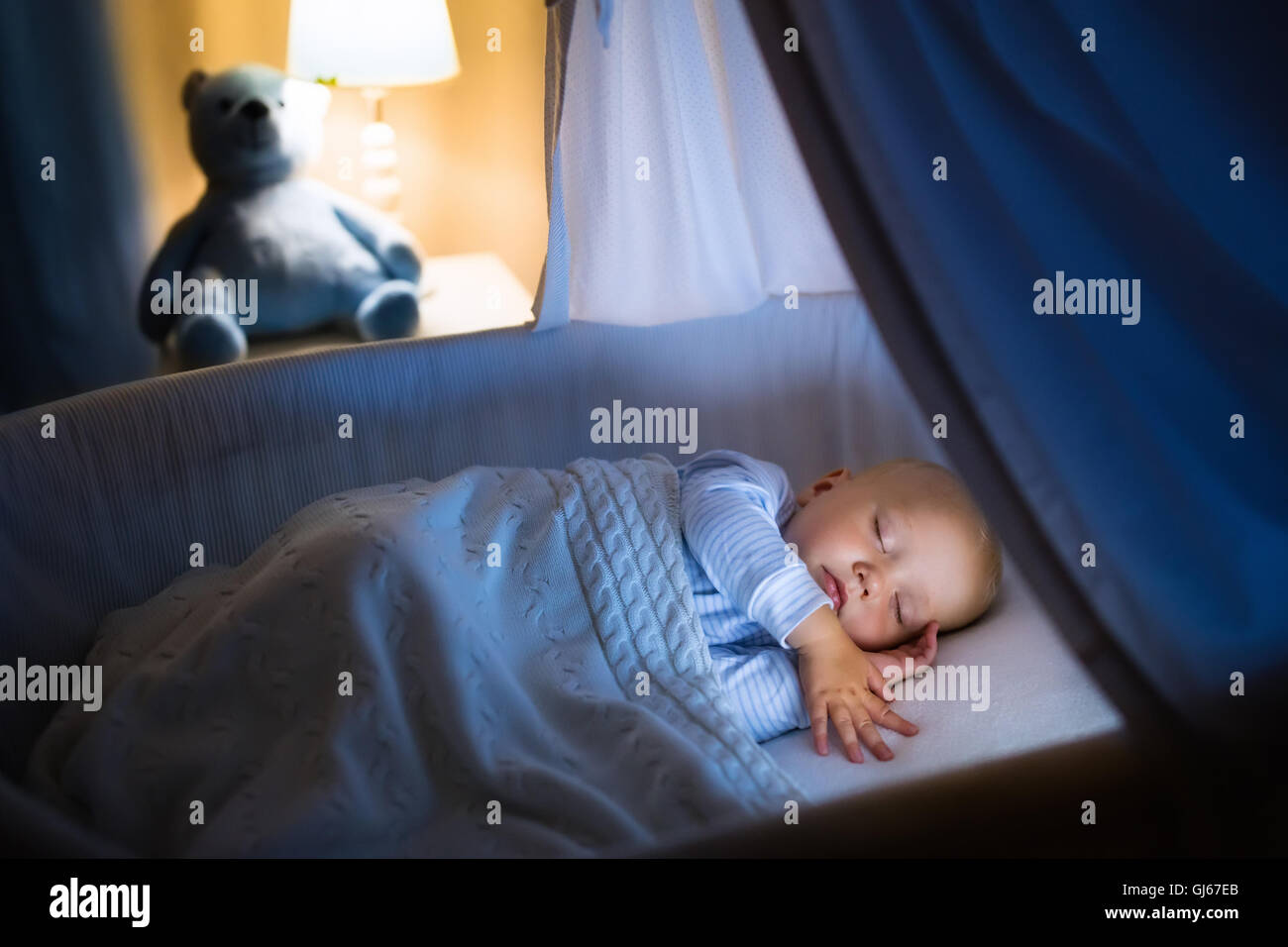 Adorable baby sleeping in blue with canopy at night. Little