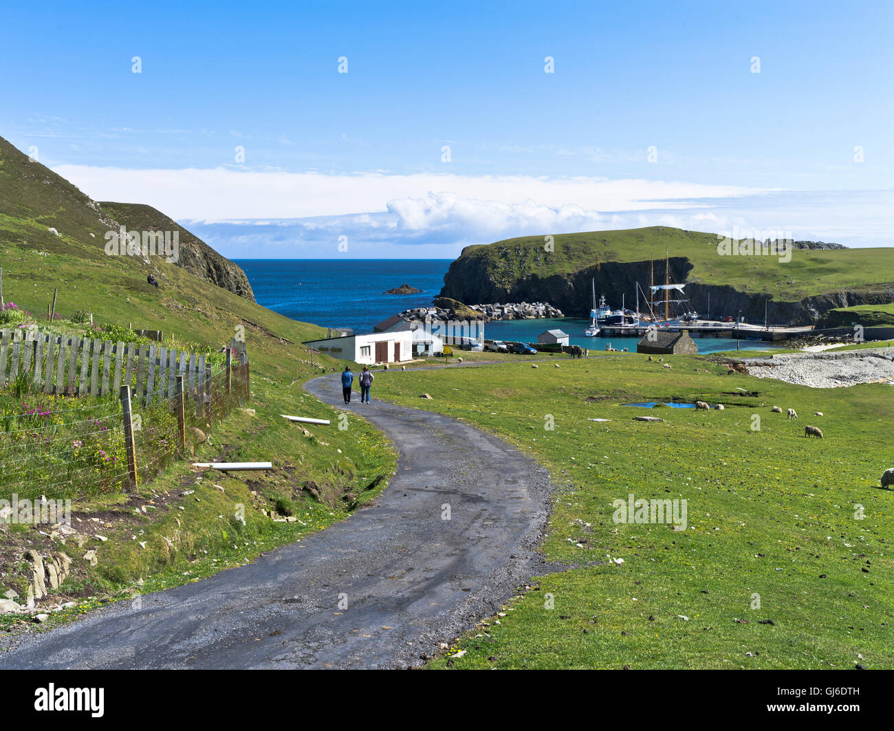 dh  FAIR ISLE SHETLAND Couple walking road to North Haven harbour  pier Stock Photo