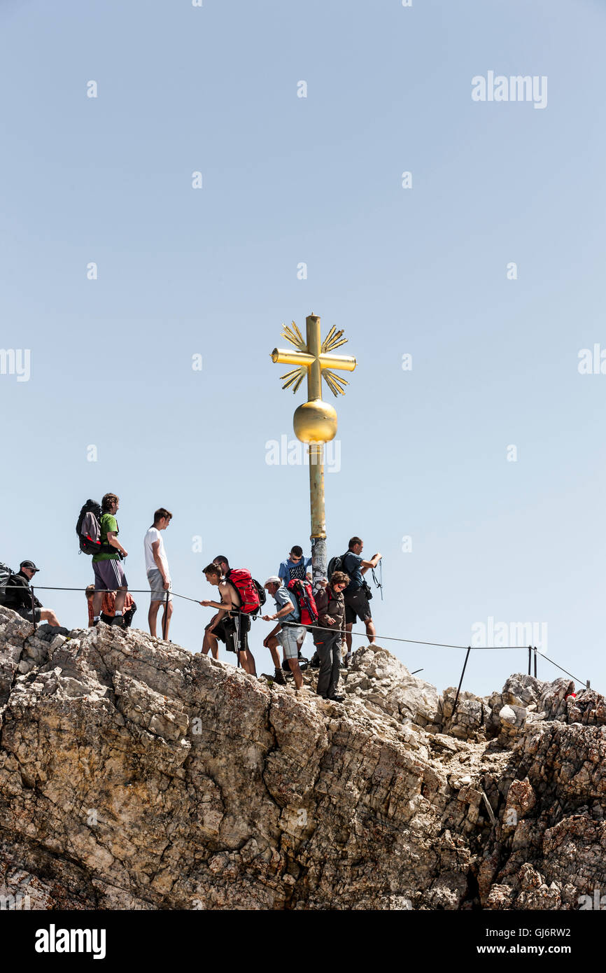 Mountaineer on the summit cross of 'Zugspitze' Stock Photo