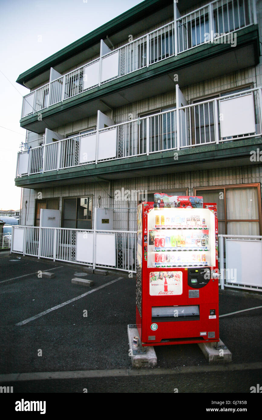In front of this apartment bulding a sole vending machine that glows as the sun sets, here in