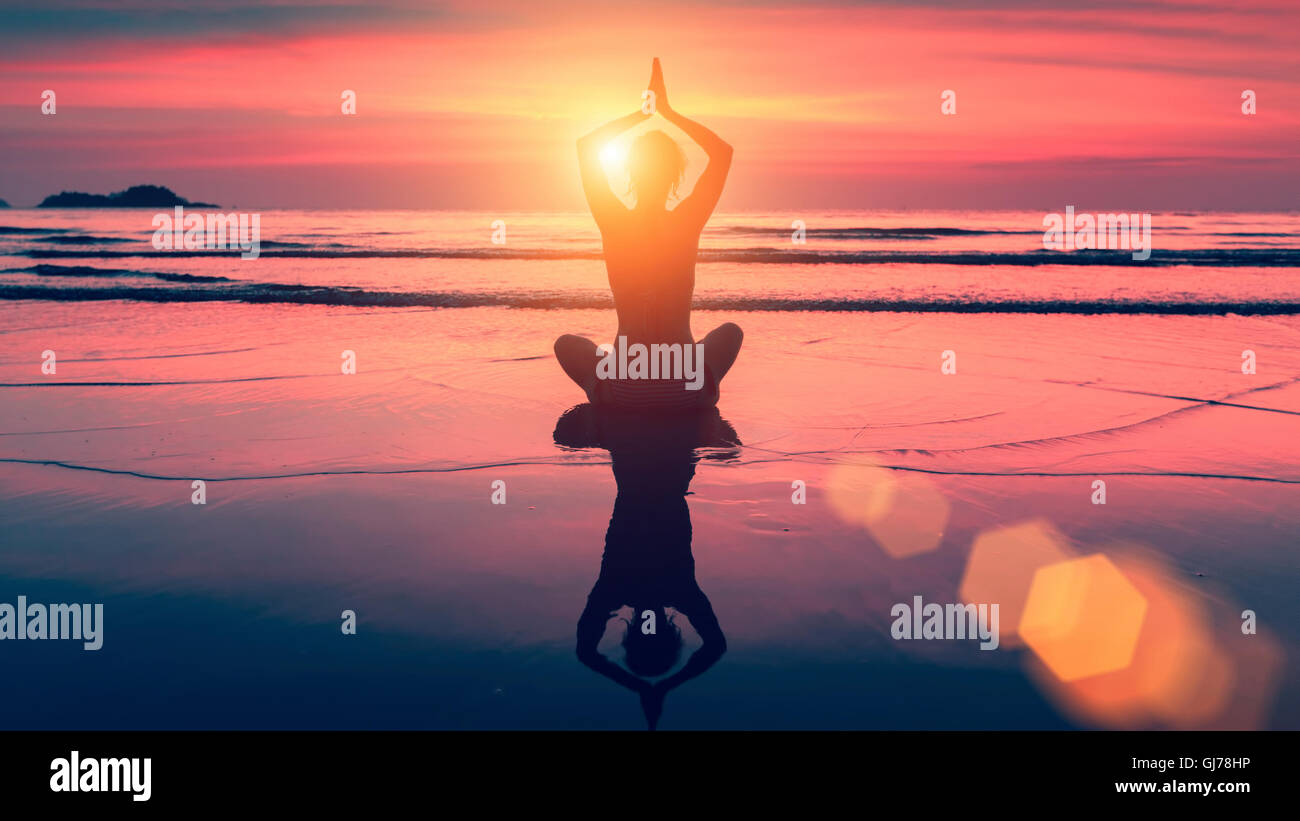 Silhouette yoga woman in Lotus pose on beach during sunset. With the ...