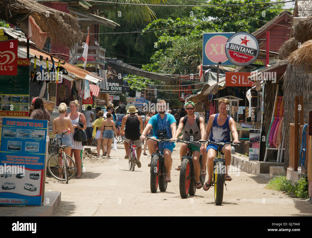 Three cyclists with sand tyres main shopping street Gili Trawangan Indonesia Stock Photo