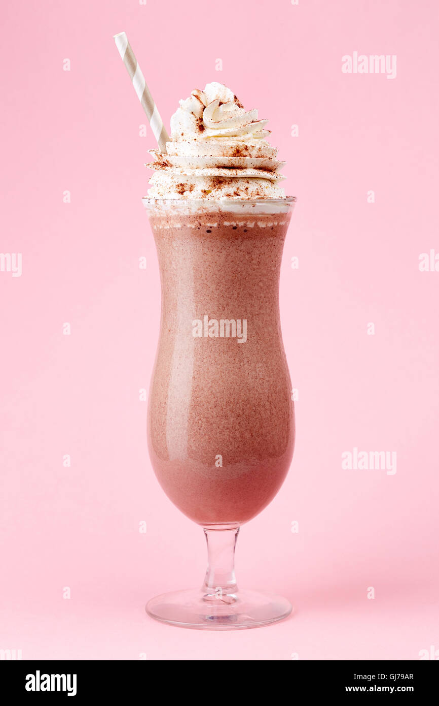 Glass of cold chocolate milkshake with whipped cream on pink background Stock Photo