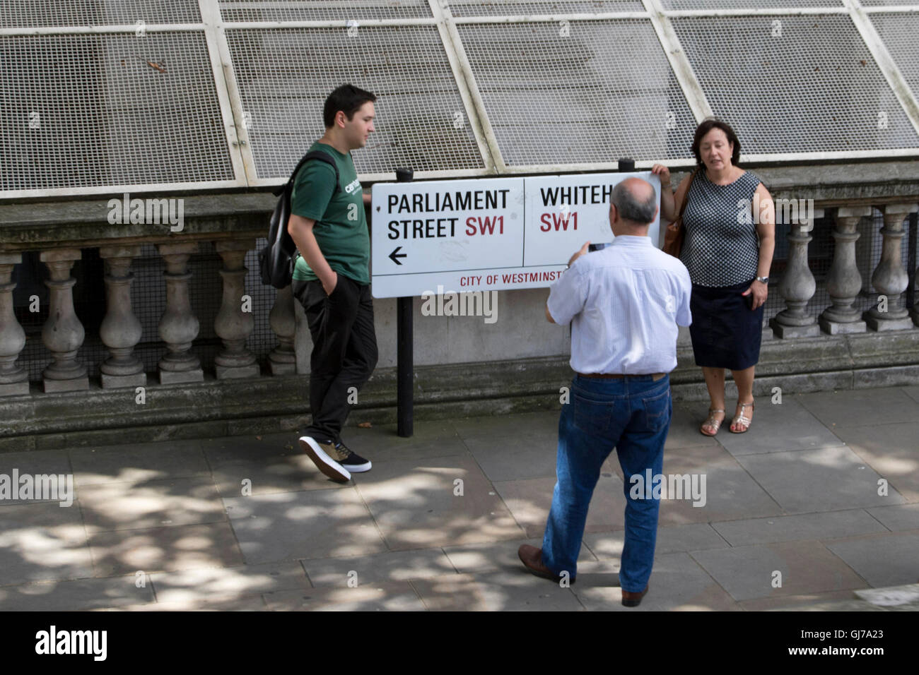 Tourists taking photographs of London street sign of Parliament Street and Whitehall Stock Photo