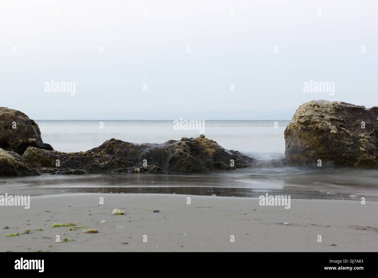 stone in the sea water under the oncoming wave Stock Photo