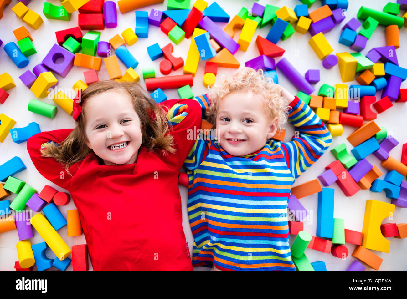 Happy preschool age children play with colorful plastic toy blocks. Creative kindergarten kids build a block tower. Stock Photo