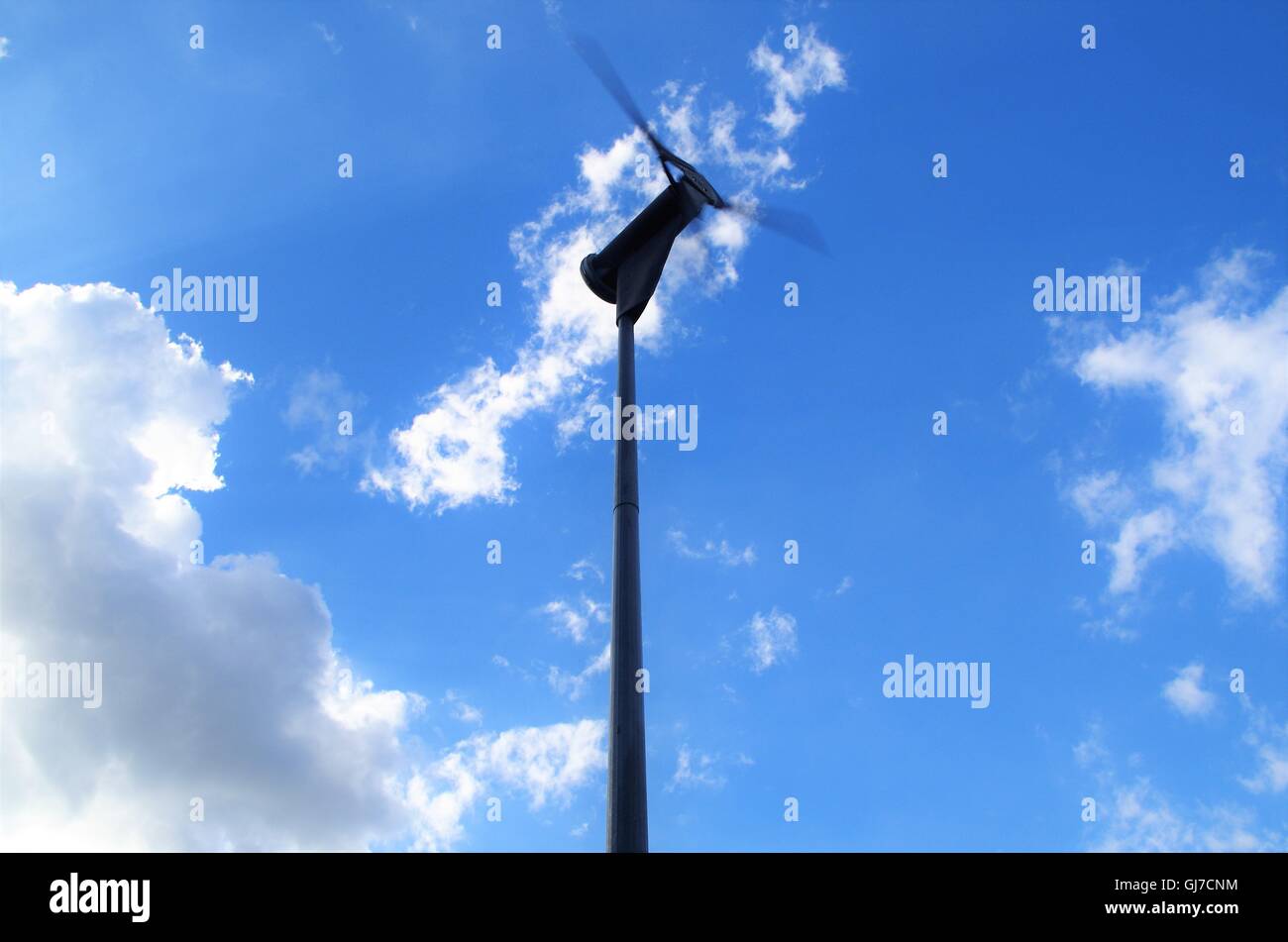 Wind Turbine Against Blue Sunny Skies With A Few Clouds Stock Photo - Alamy