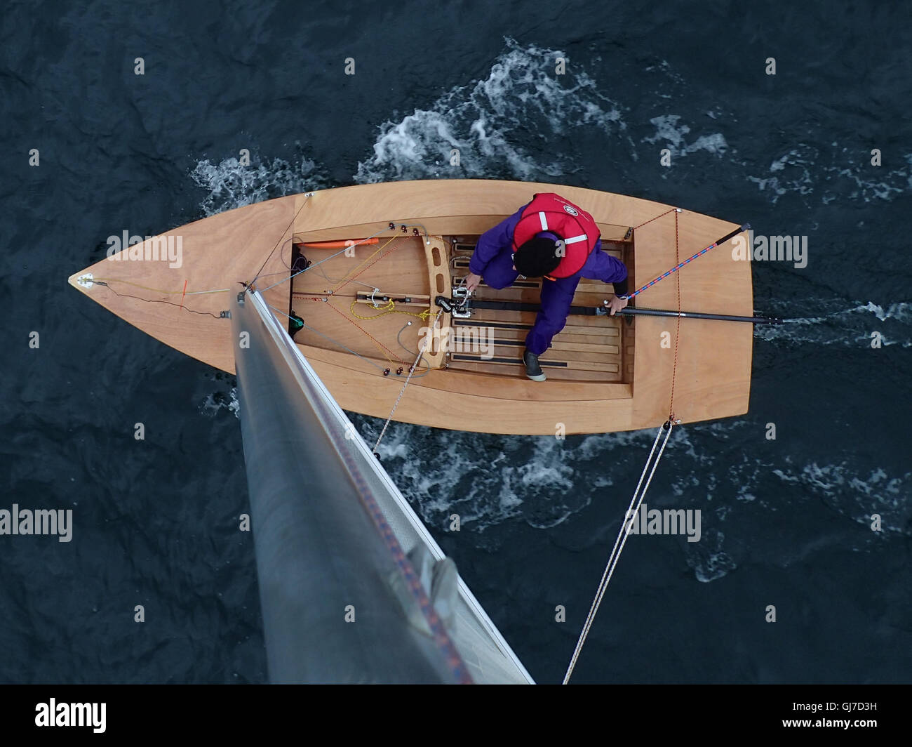View downwards from top of mast of Streaker Class Sailing Dinghy, with male helm in his sixties Stock Photo