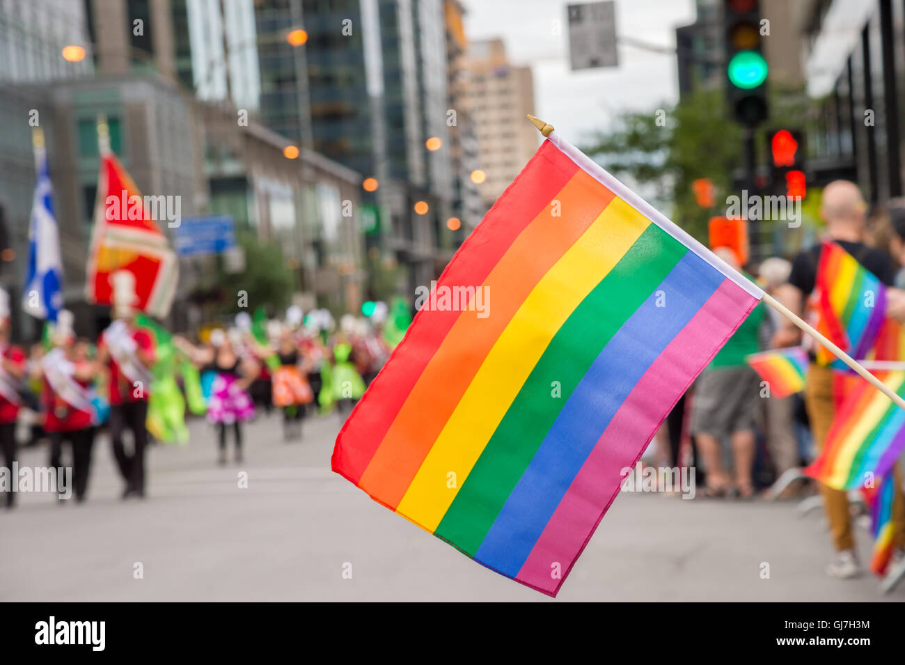 Gay rainbow flags at Montreal gay pride parade with blurred spectators in the background Stock Photo