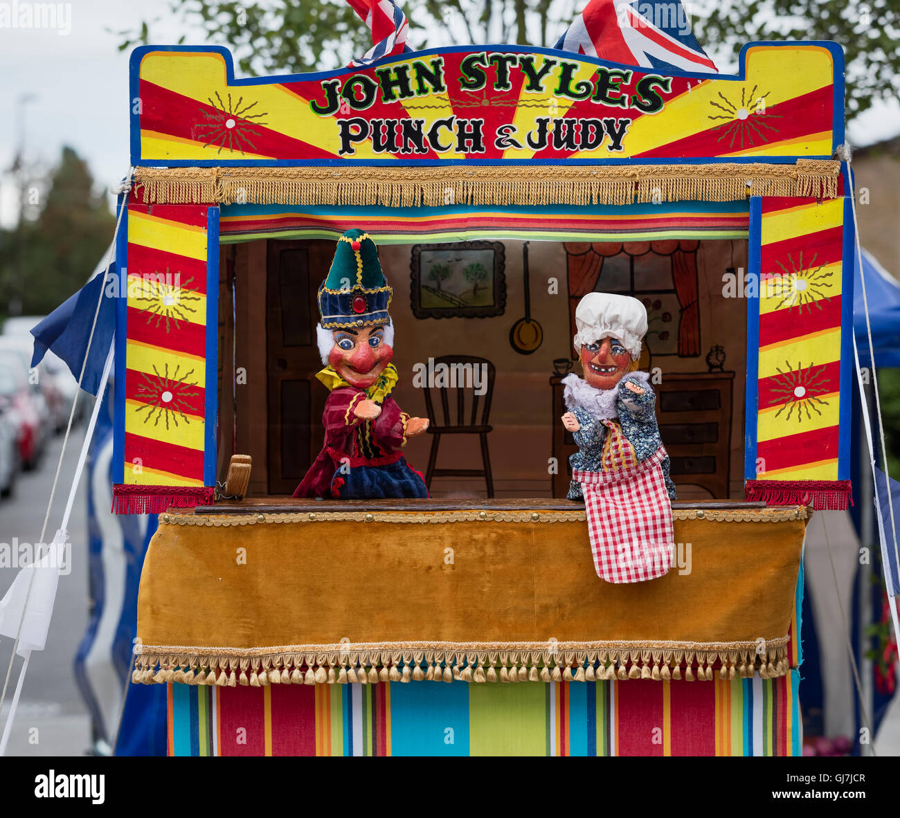 Mr Punch with Judy holding the baby in front of a Punch and Judy puppet