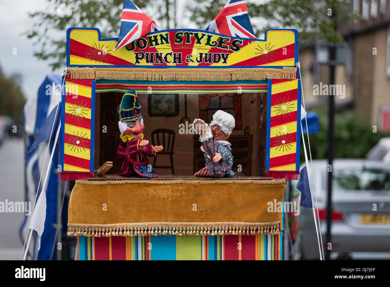 Mr punch with Judy holding the baby in front of a Punch and Judy glove