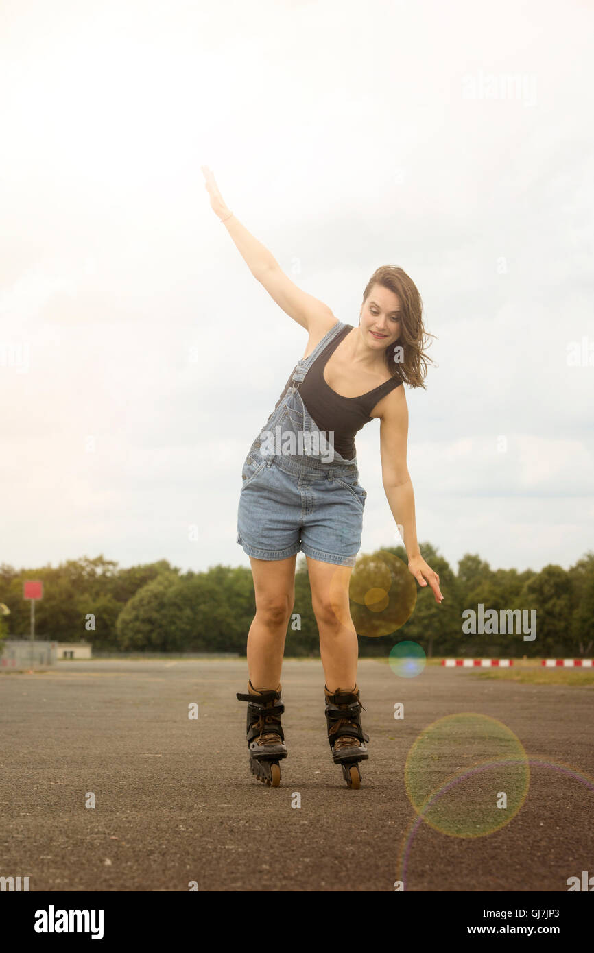 young brunette woman is rollerblading on a street Stock Photo