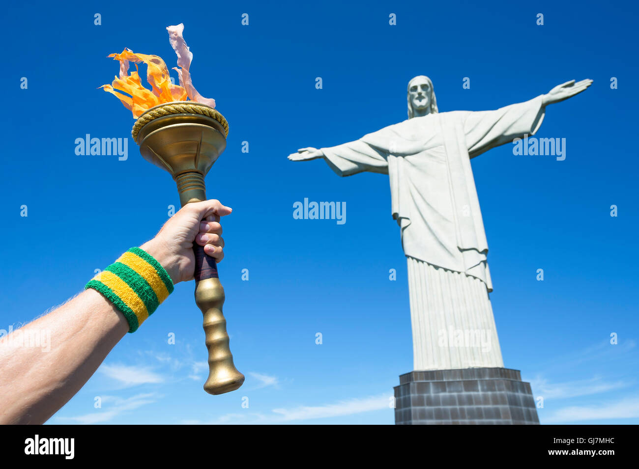 RIO DE JANEIRO - MARCH 21, 2016: Torchbearer holding torch in front of statue of Christ the Redeemer at Corcovado. Stock Photo