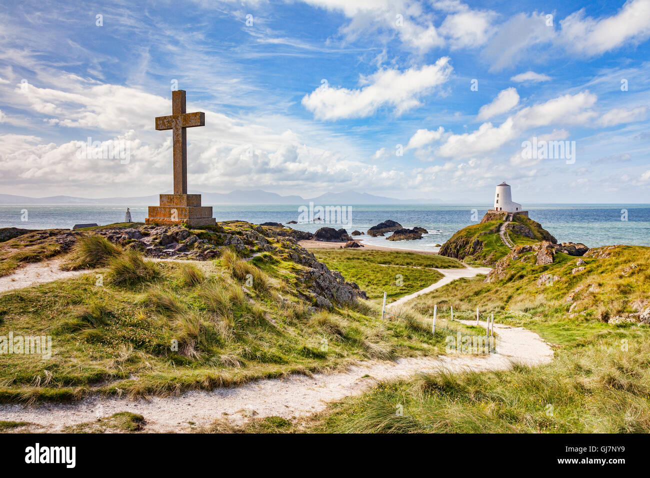 A large Christian cross and Twr Mawr, the old lighthouse on the tidal island of Ynys Llanddwyn, Newborough, Anglesey, Wales, UK Stock Photo