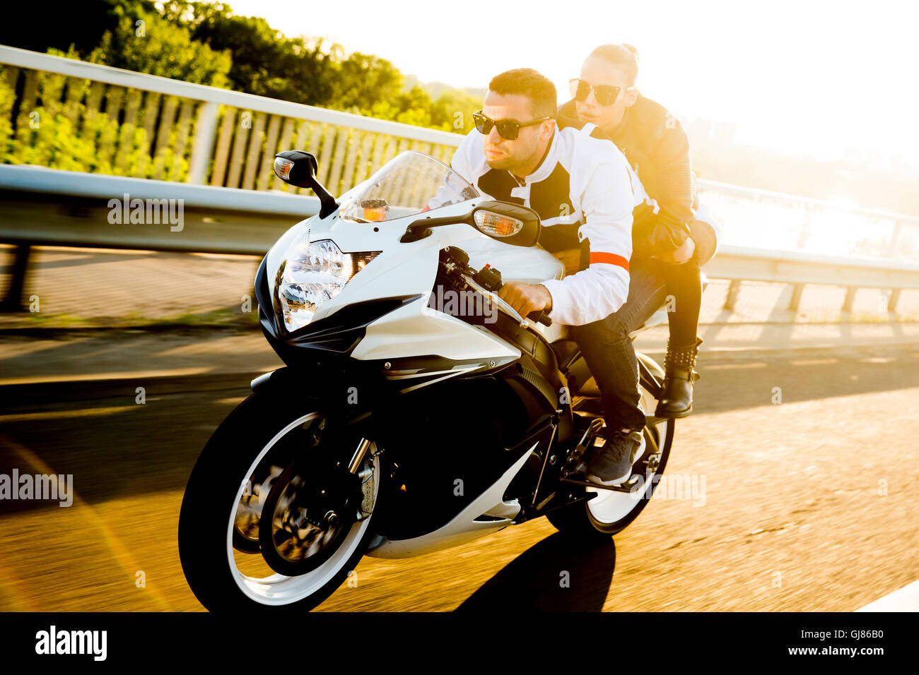Man and woman wearing  leather jackets and stylish sunglasses riding on motorcycle Stock Photo