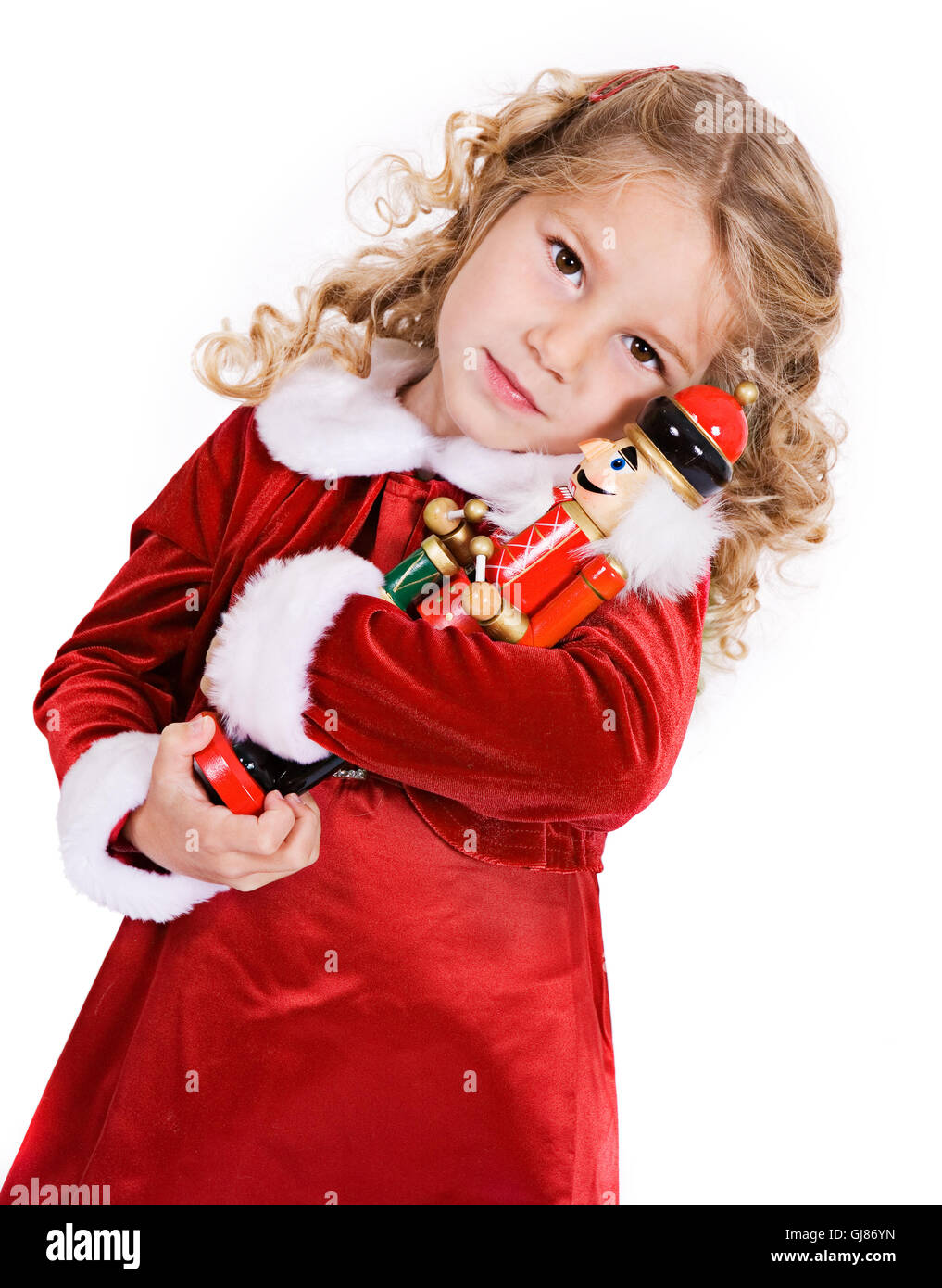 Little girl in red velvet holiday dress celebrates Christmas, isolated on white. Stock Photo