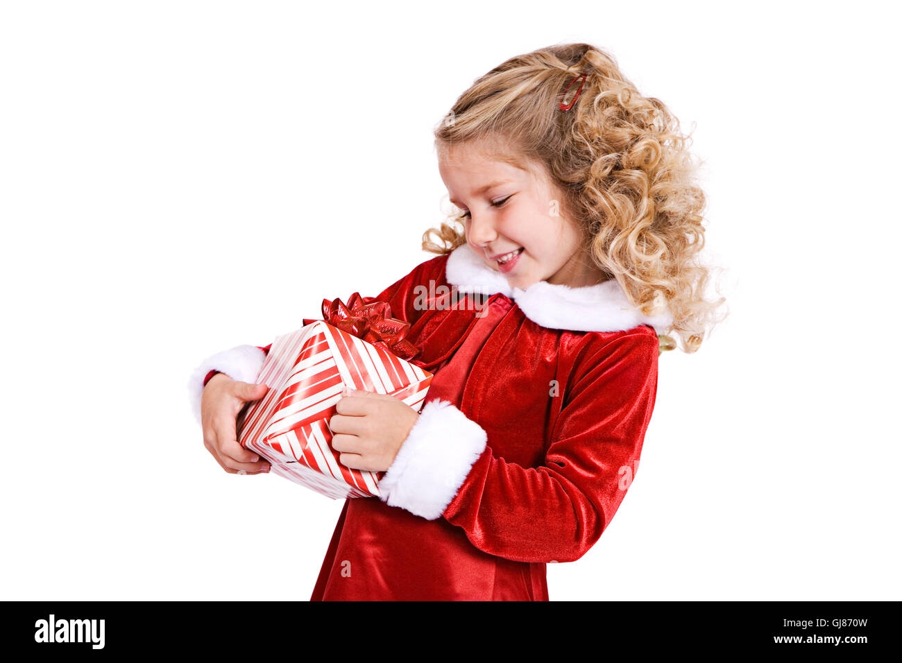Little girl in red velvet holiday dress celebrates Christmas, isolated on white. Stock Photo