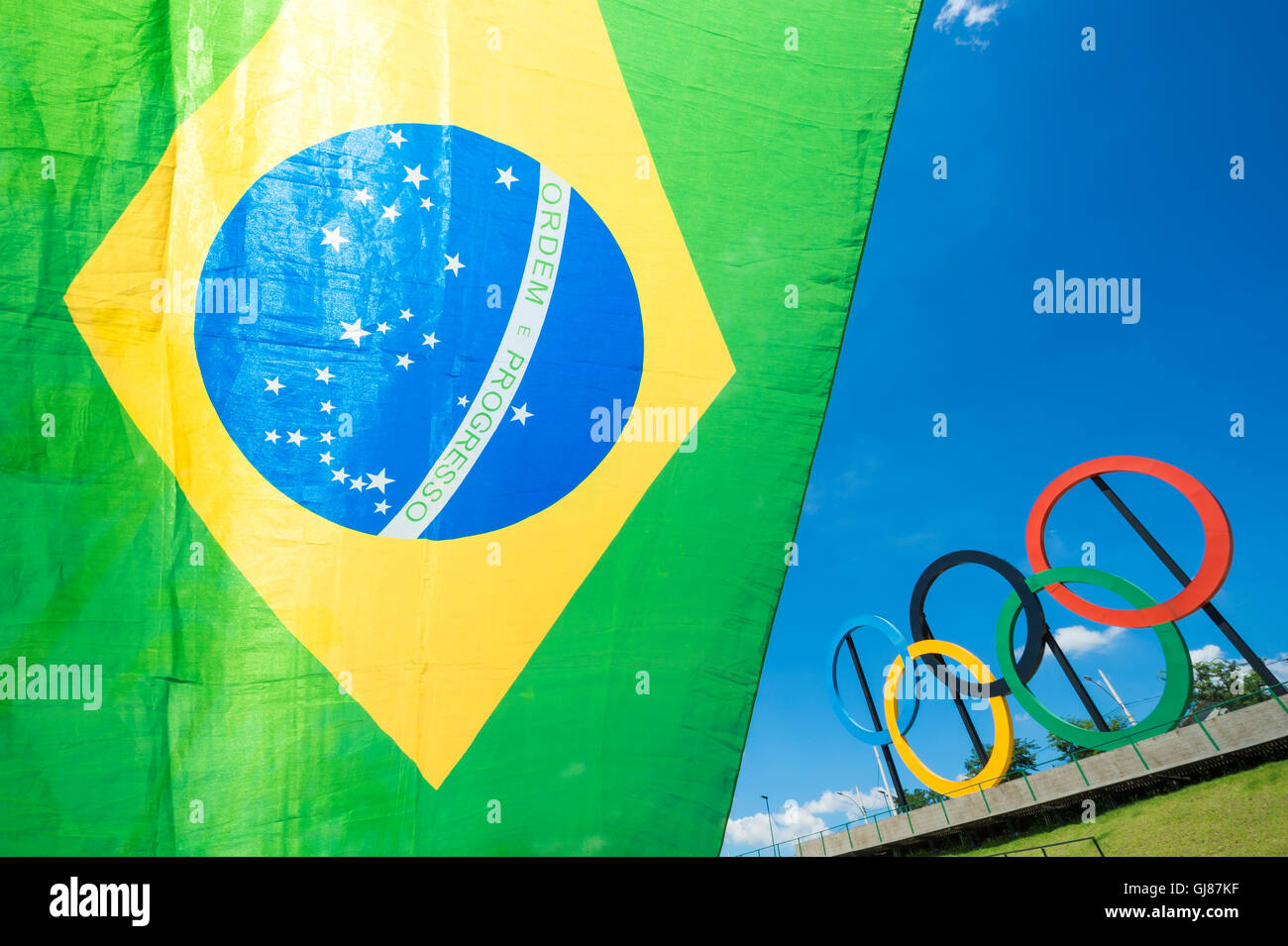 RIO DE JANEIRO - MARCH 18, 2016: A Brazil flag hangs in front of a display of Olympic rings in Parque Madureira Park, Zona Norte Stock Photo