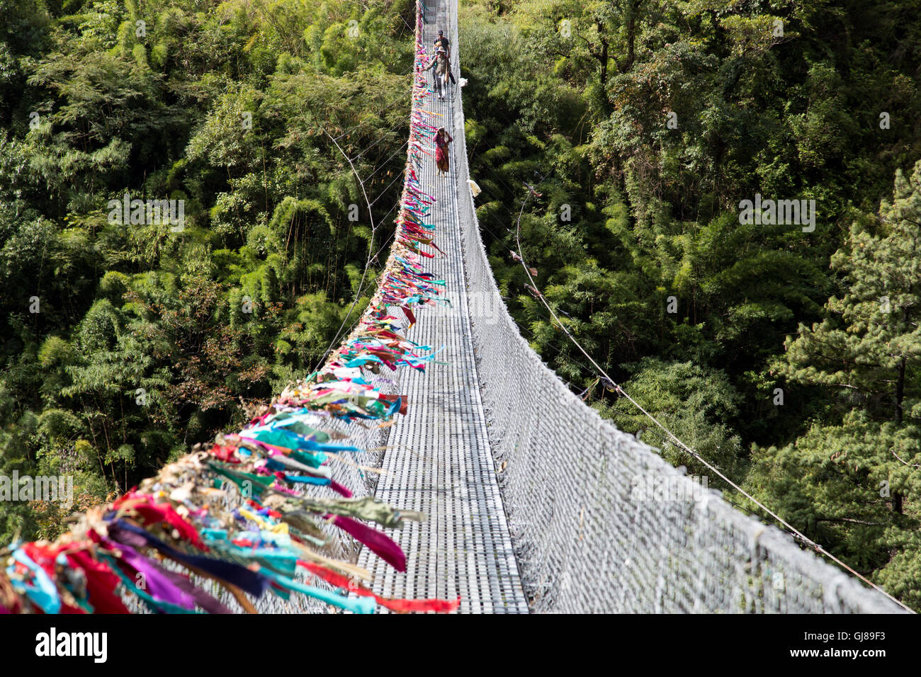 Ghasa, Nepal - November 05, 2014: Local people crossing a suspension bridge on the Annapurna Circuit Stock Photo