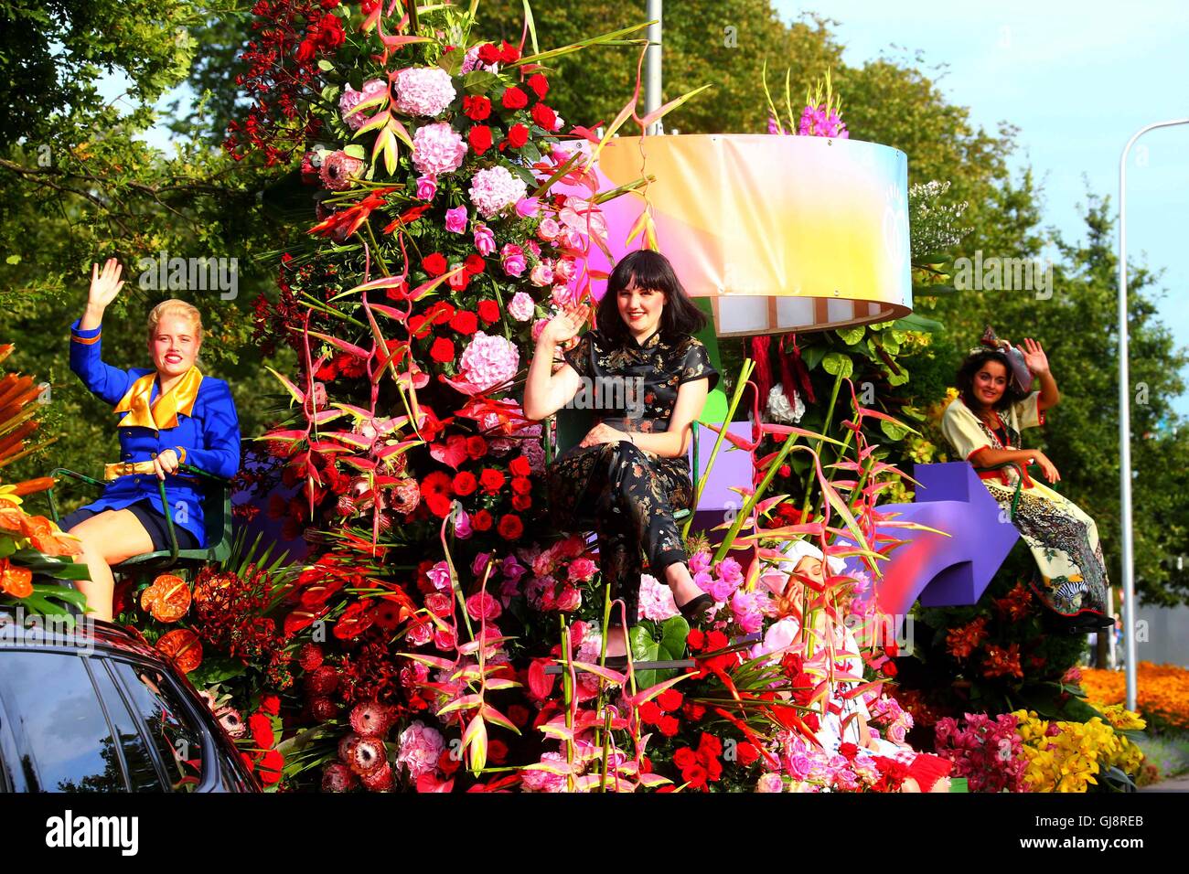 The Hague, Netherlands. 13th Aug, 2016. Three women greet the audience on a float during the Flower Parade in Noordwijk, the Netherlands, on Aug. 13, 2016. The annual Flower Parade since 1946 was held in Rijnsburg, Katwijk and Noordwijk of the Netherlands on Saturday. Credit:  Gong Bing/Xinhua/Alamy Live News Stock Photo