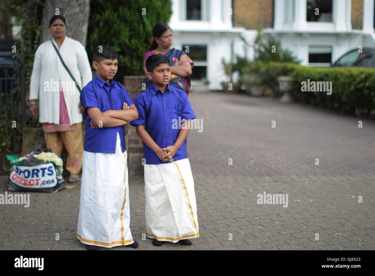 Ealing, London, UK. 14th Aug, 2016.  Two boys watching the chariot procession, the culmination of the annual Shri Kanagathurkkai Amman Temple (SKAT) festival of Thaipusam in West Ealing. The festival attracts thousands of Hindu devotees to West Ealing from all over the world. Credit:  Roger Garfield/Alamy Live News Stock Photo
