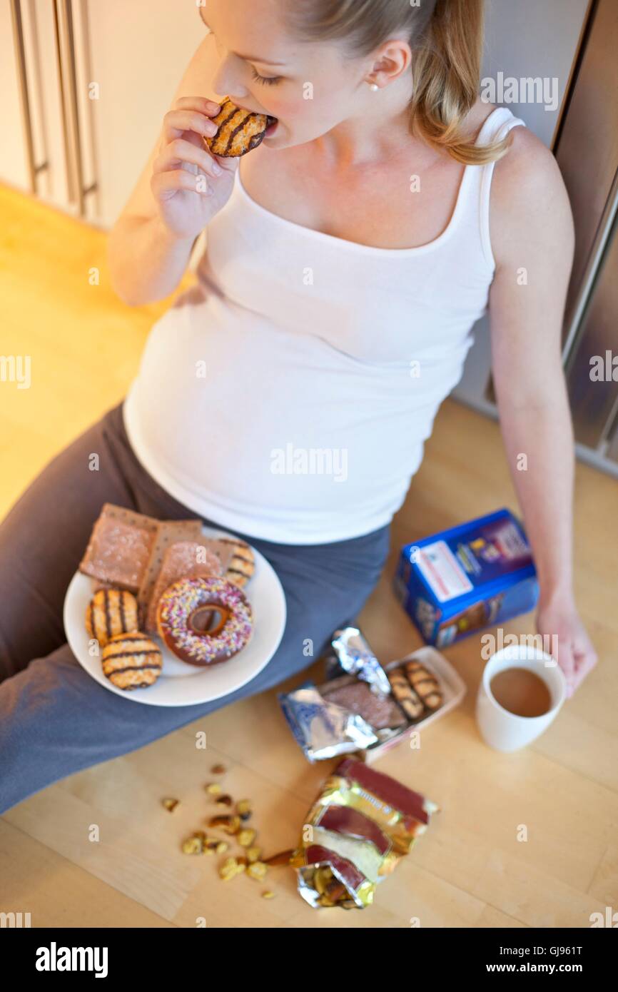 MODEL RELEASED. Pregnant woman eating biscuit Stock Photo Alamy