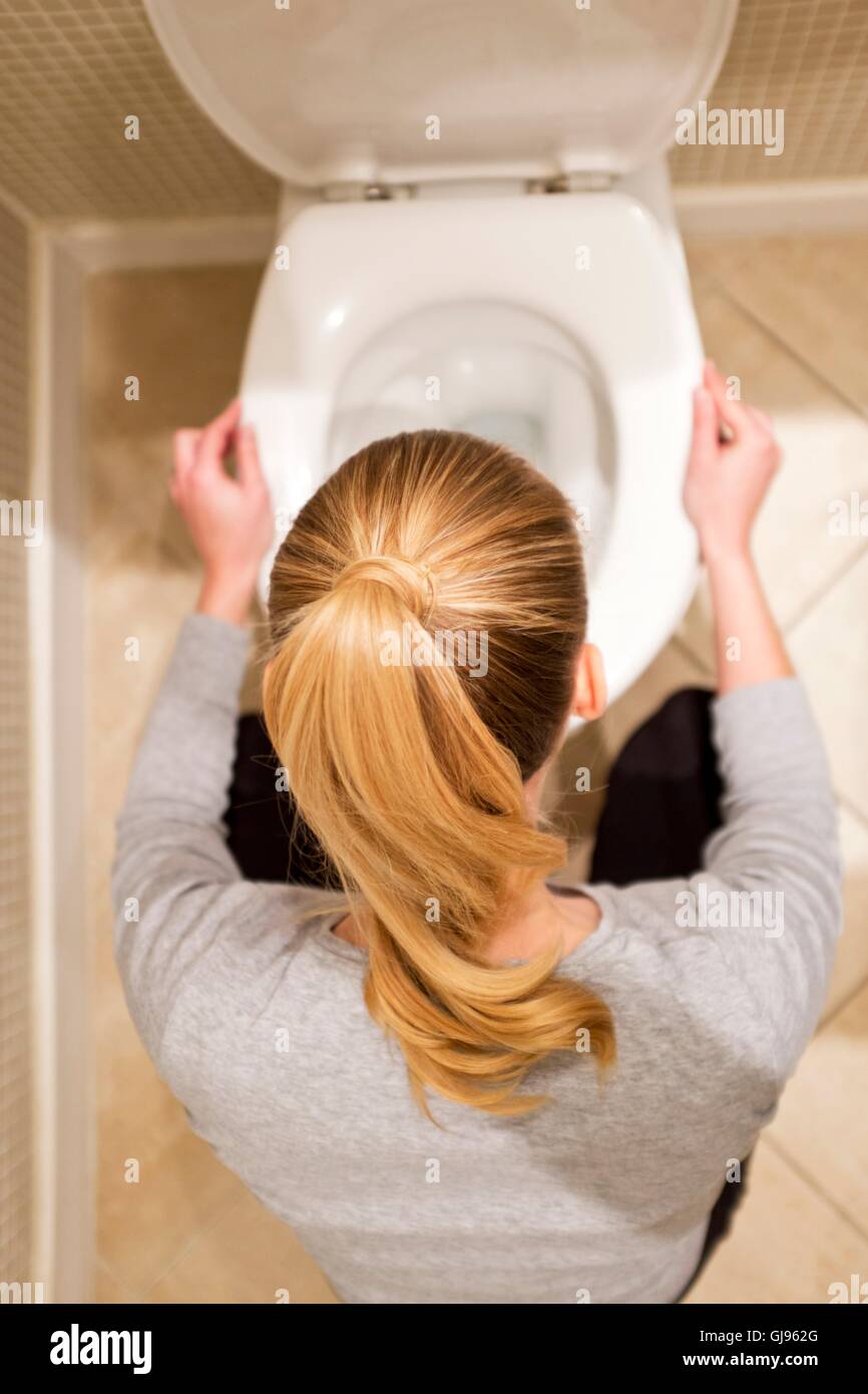 MODEL RELEASED. Pregnant woman with morning sickness by toilet. Stock Photo