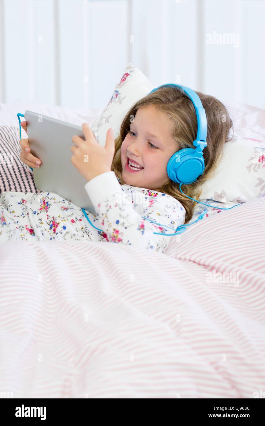 PROPERTY RELEASED. MODEL RELEASED. Daughter in bed with digital tablet. Stock Photo