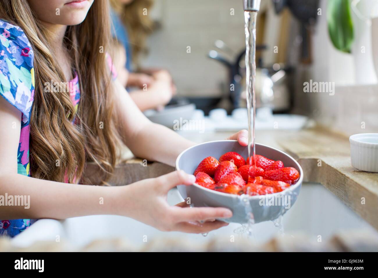 PROPERTY RELEASED. MODEL RELEASED. Girl washing fresh strawberries in the sink. Stock Photo