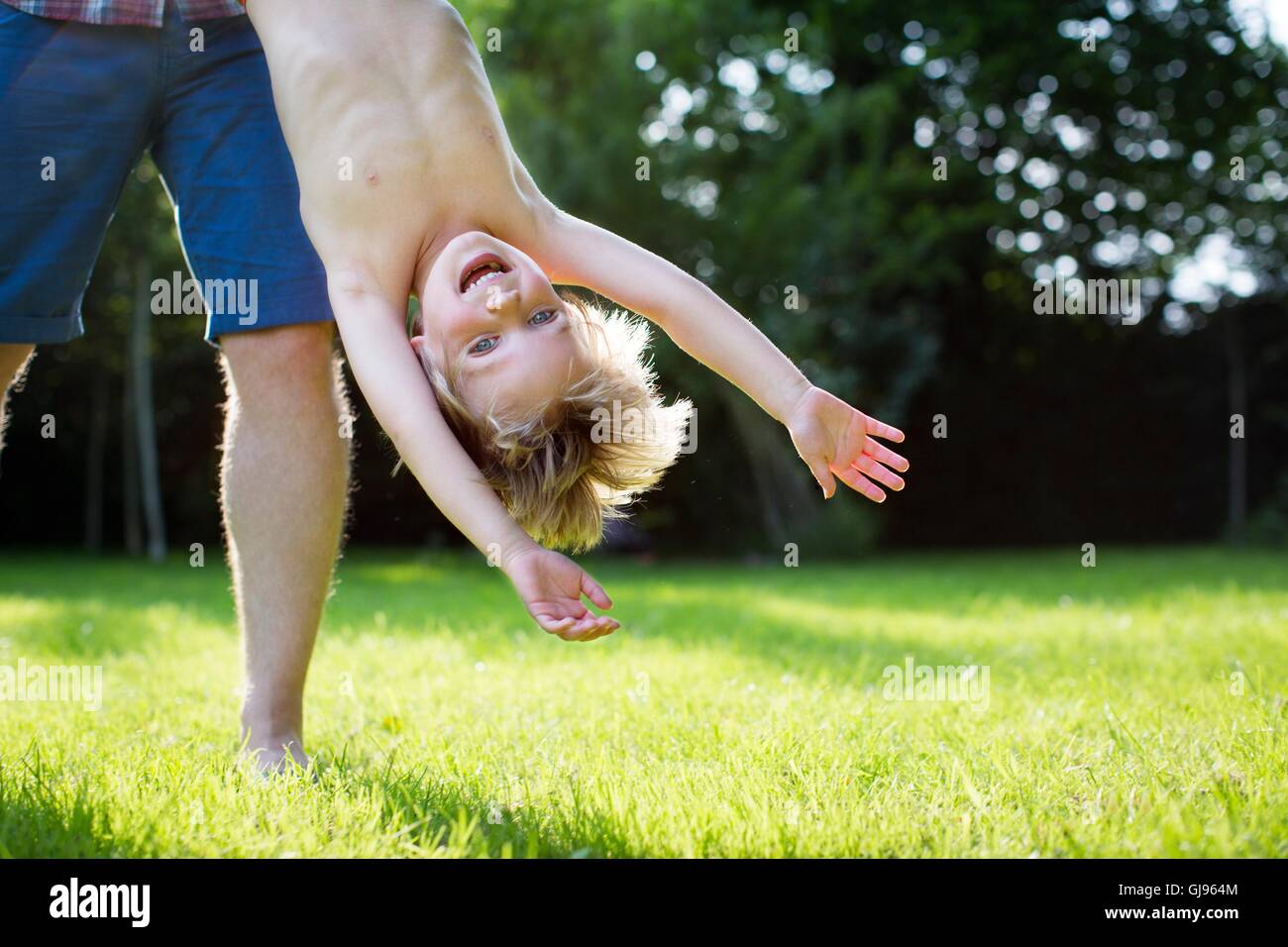 PROPERTY RELEASED. MODEL RELEASED. Father holding son upside down in the garden. Stock Photo