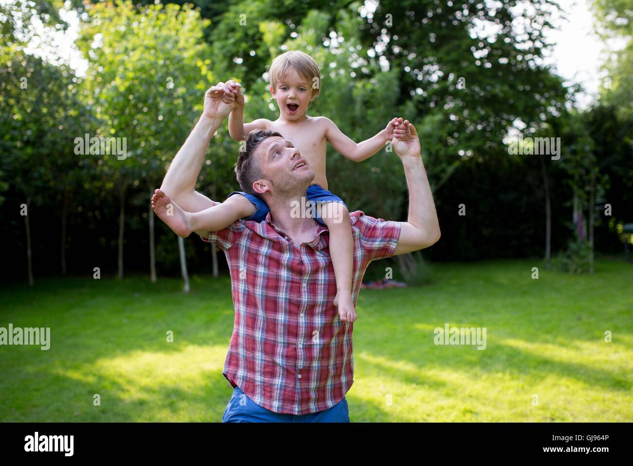 PROPERTY RELEASED. MODEL RELEASED. Father carrying son on his shoulders in the garden. Stock Photo