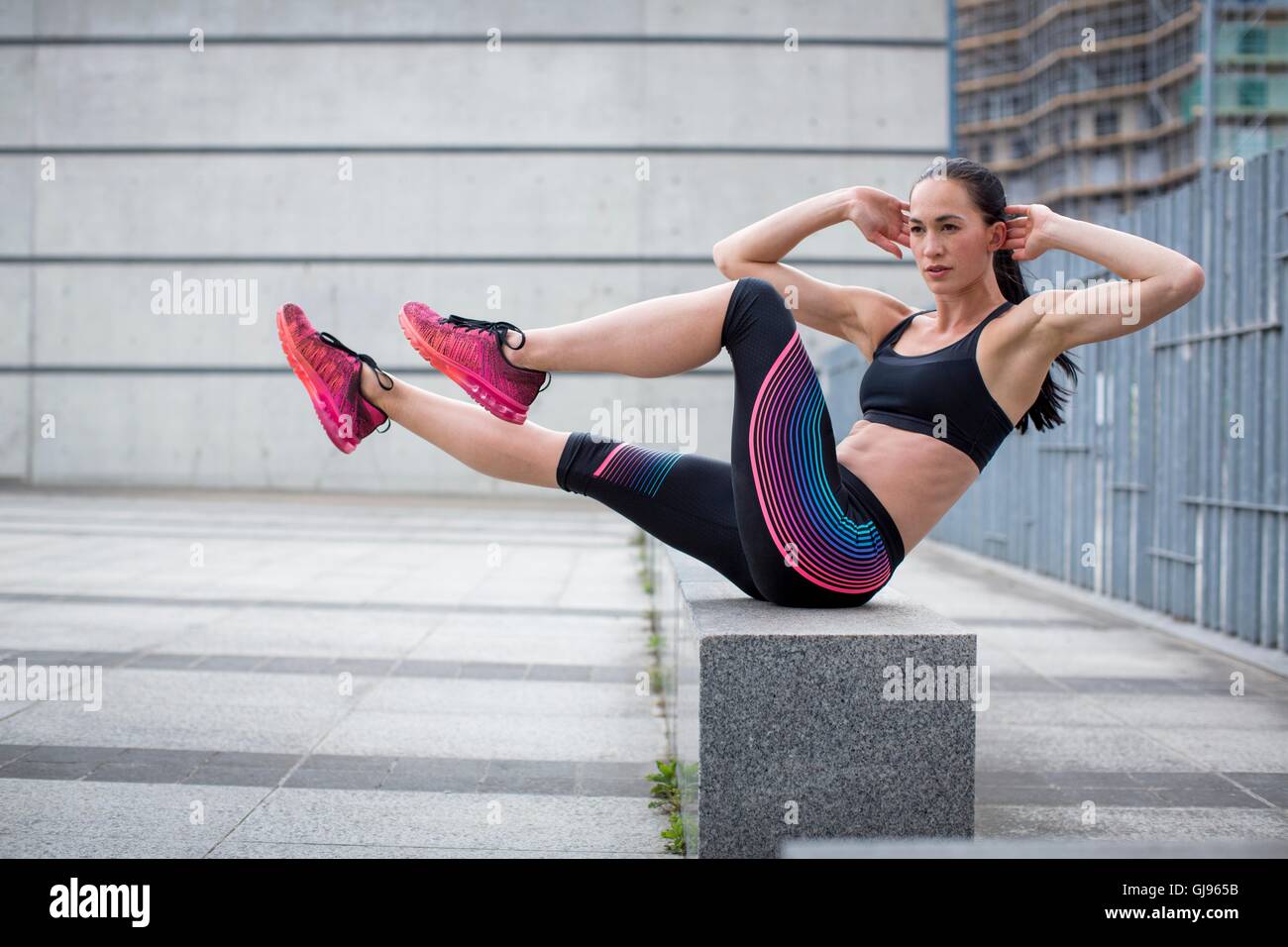 MODEL RELEASED. Young woman exercising on wall. Stock Photo