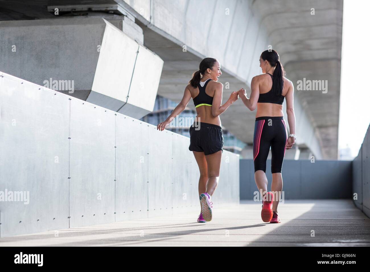 MODEL RELEASED. Two young women wearing sports wear in urban scene. Stock Photo