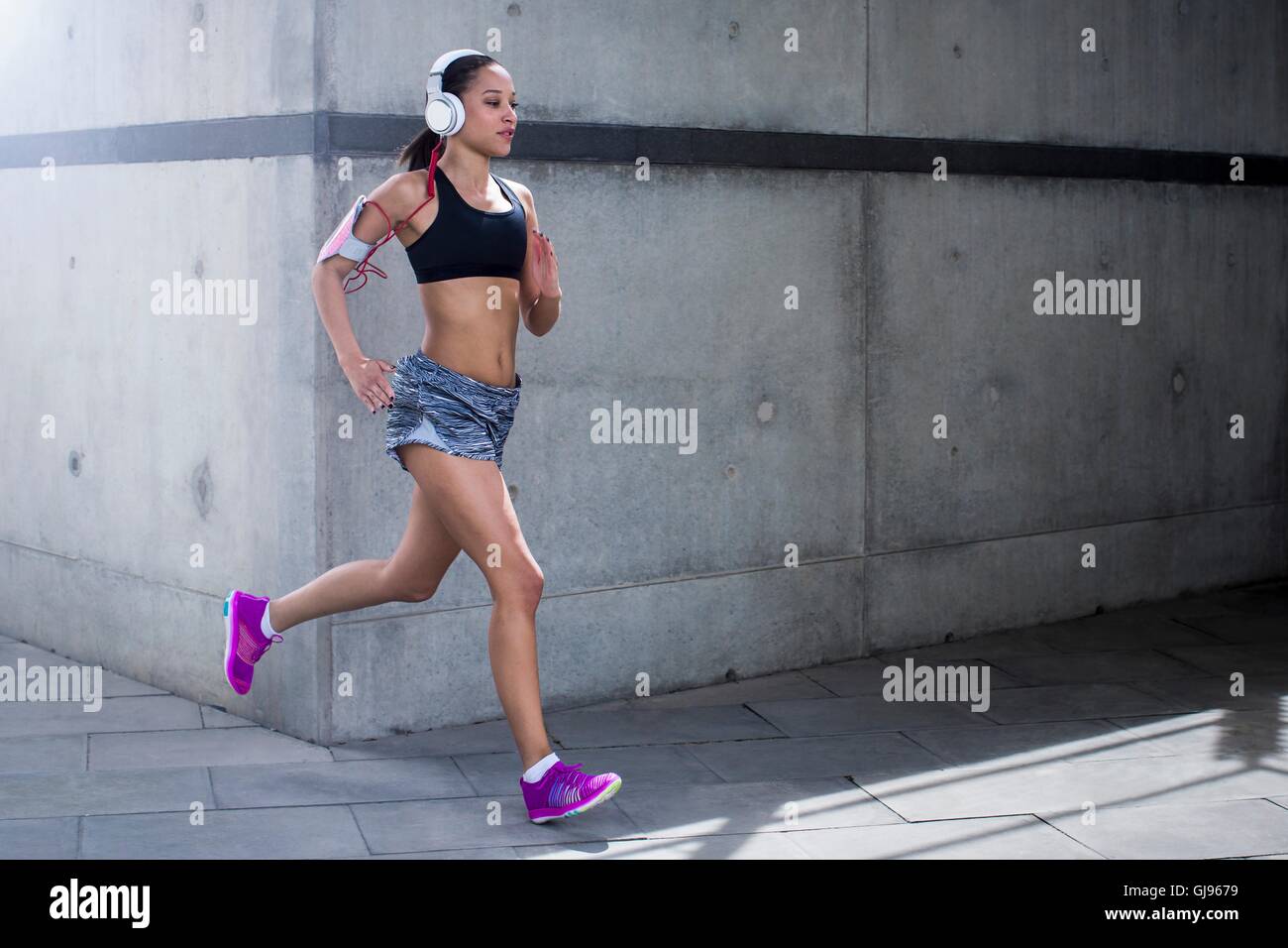 MODEL RELEASED. Young woman wearing headphones running. Stock Photo