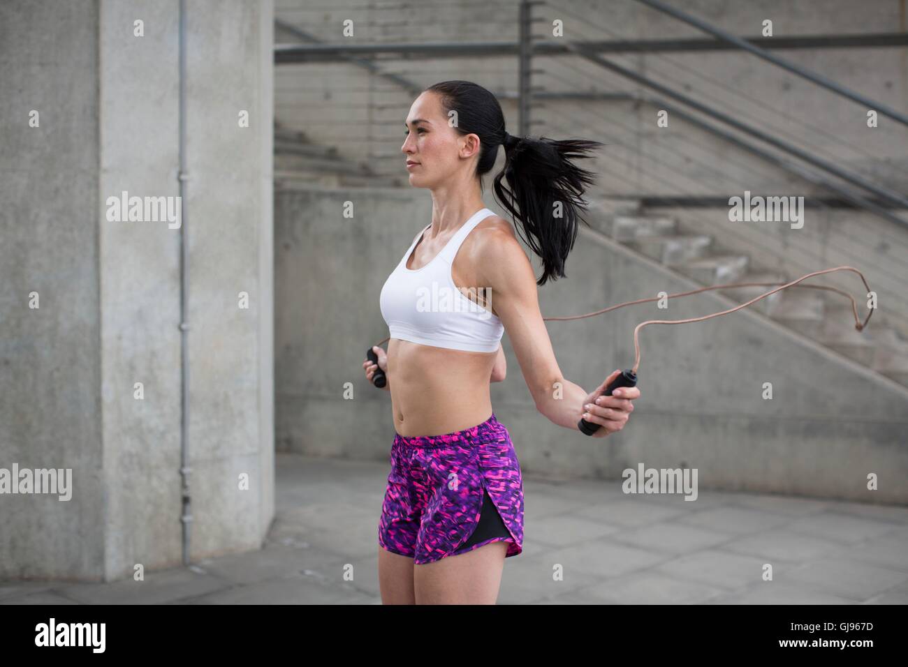 MODEL RELEASED. Young woman skipping with rope. Stock Photo