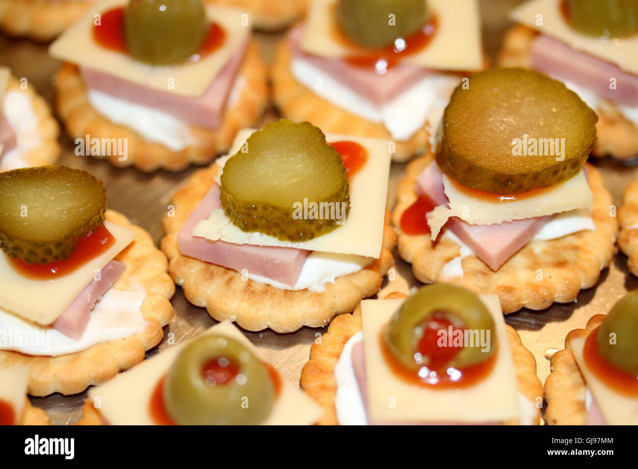 Closeup of crackers with cheese, ham, olives and ketchup Stock Photo
